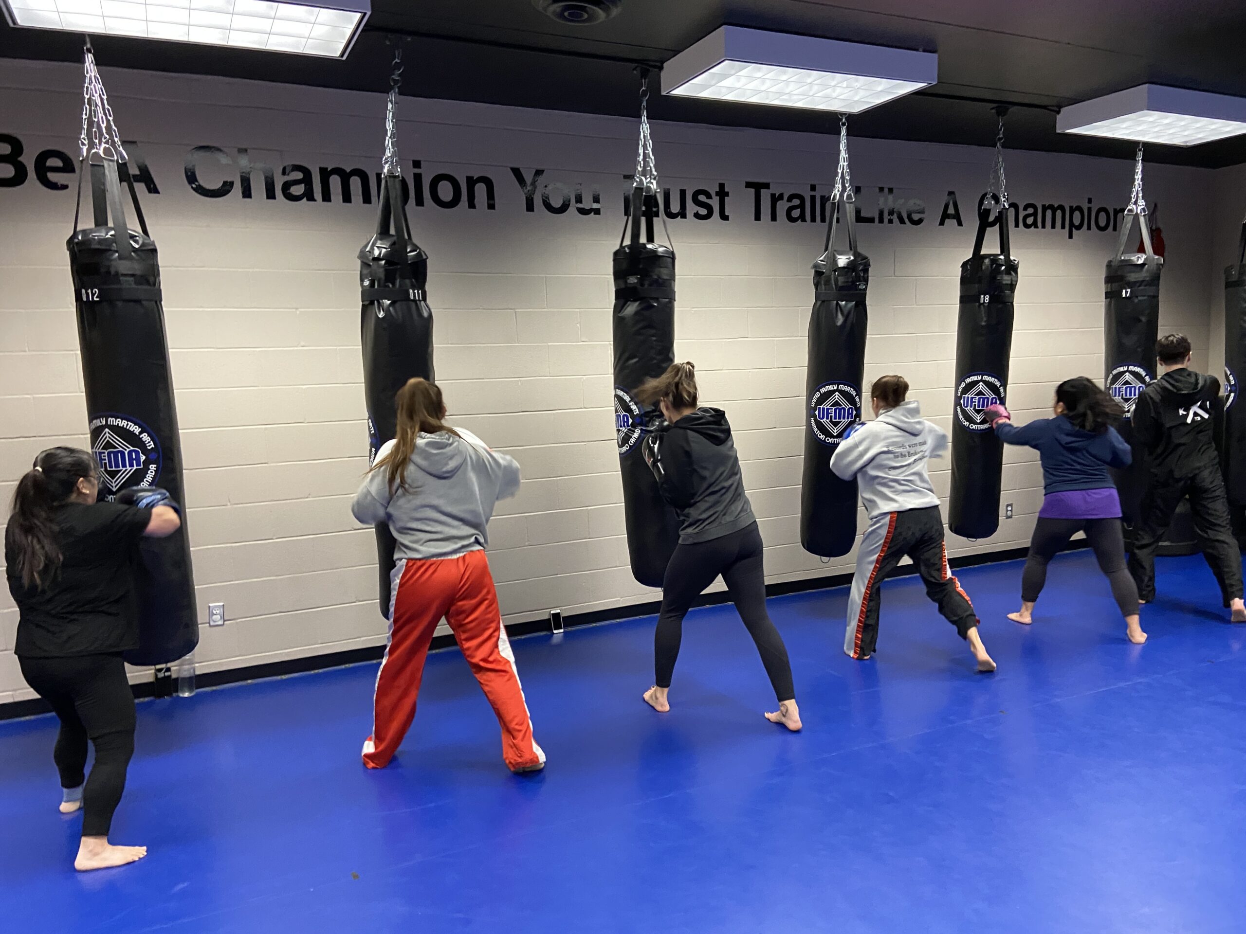Six students hitting the heavy bags in kickboxing class